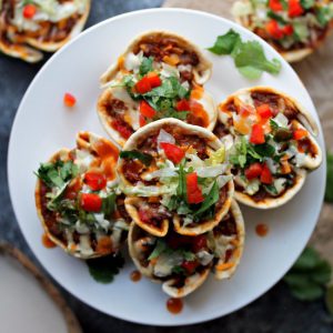 Close-up of crispy vegan taco cups filled with seasoned meat, vegan cheese, and fresh toppings.