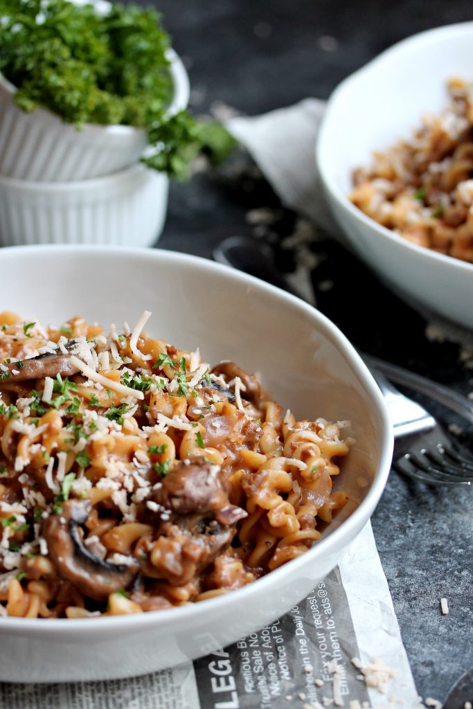 A bowl of vegan beef stroganoff topped with fresh parsley and vegan parmesan.