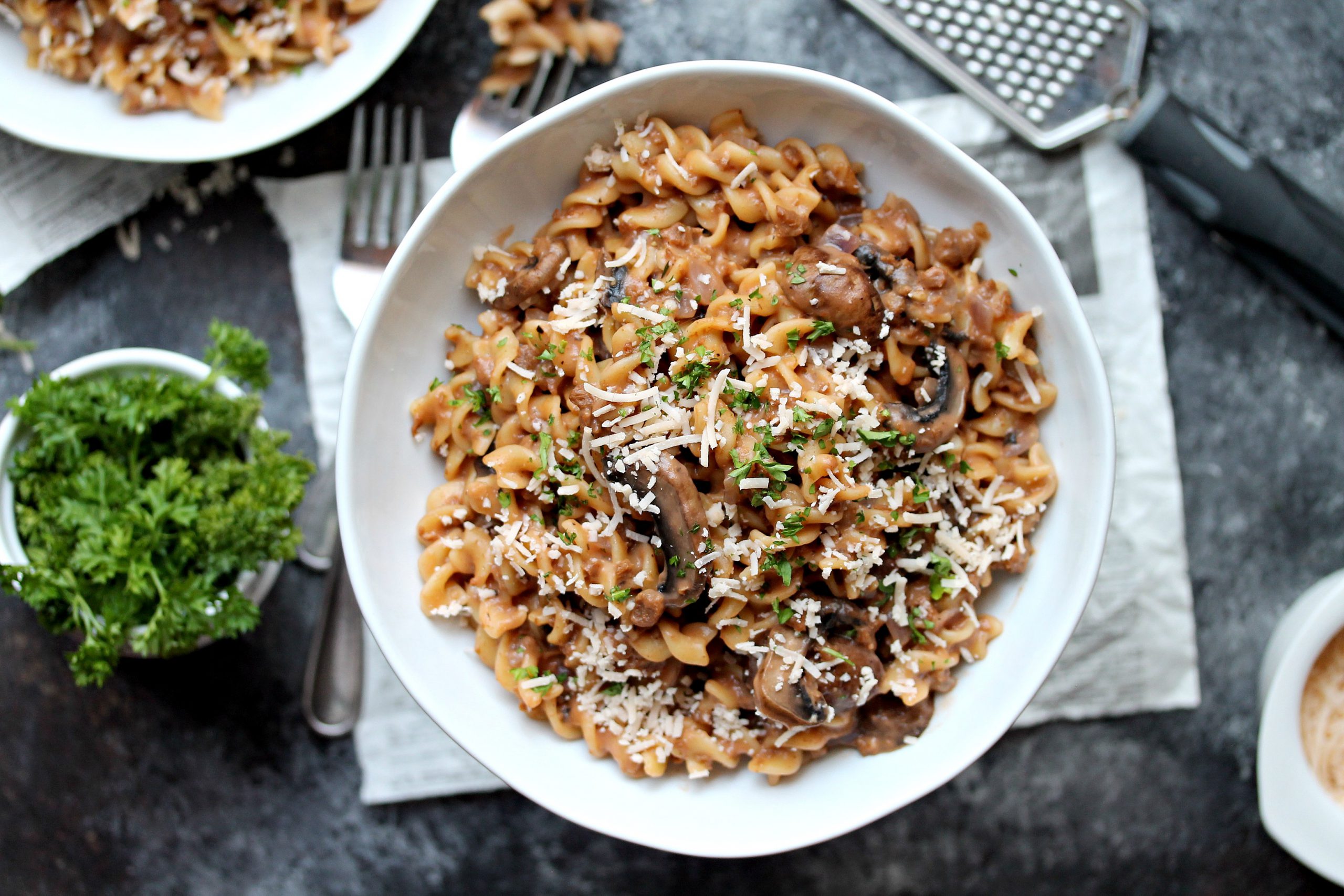 A bowl of vegan beef stroganoff topped with fresh parsley and vegan parmesan.