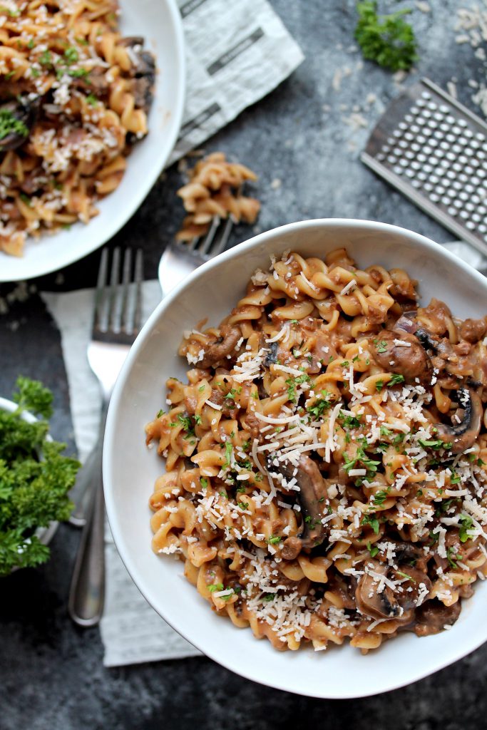 A bowl of vegan beef stroganoff topped with fresh parsley and vegan parmesan.