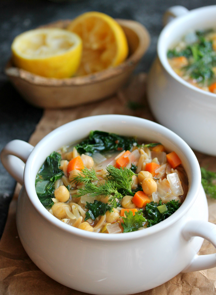 A bowl of Lemon Dill Chickpea Orzo Soup garnished with fresh dill and a lemon wedge, ready to be enjoyed.