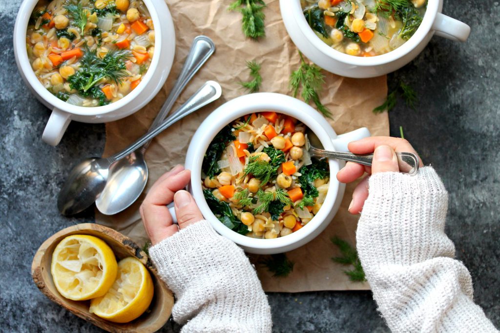 A bowl of Lemon Dill Chickpea Orzo Soup garnished with fresh dill and a lemon wedge, ready to be enjoyed.