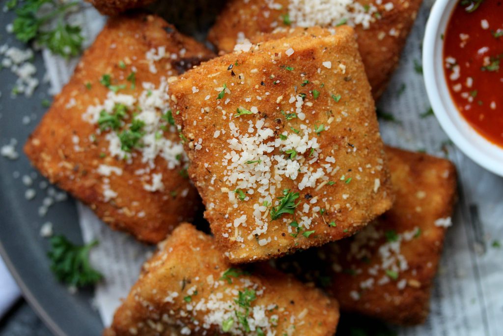 Crispy vegan lasagna fritta served with marinara sauce, garnished with fresh parsley and vegan parmesan.