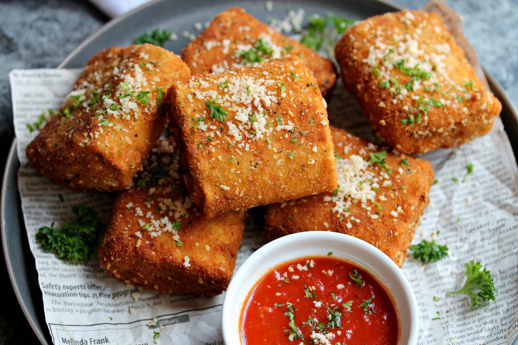 Crispy vegan lasagna fritta served with marinara sauce, garnished with fresh parsley and vegan parmesan.