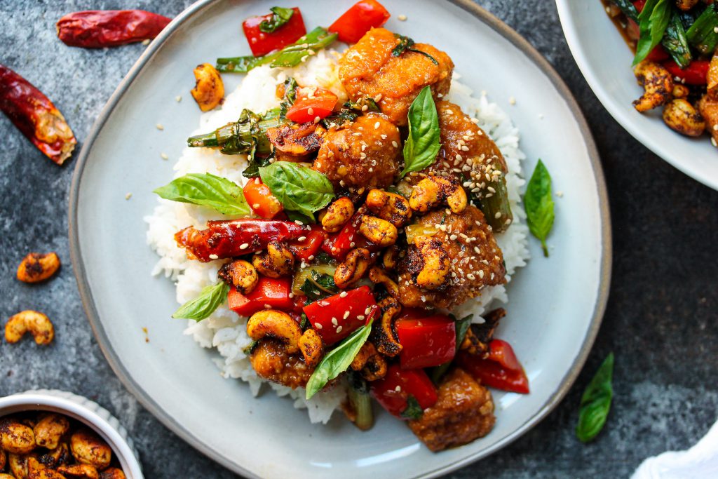 A serving of Thai Basil Tofu with Curry Roasted Cashews garnished with fresh Thai basil and toasted sesame seeds.