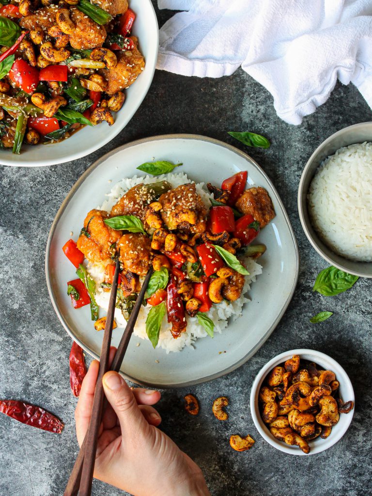 A serving of Thai Basil Tofu with Curry Roasted Cashews garnished with fresh Thai basil and toasted sesame seeds.