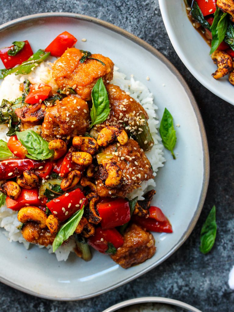 A serving of Thai Basil Tofu with Curry Roasted Cashews garnished with fresh Thai basil and toasted sesame seeds.