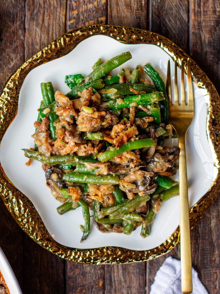 Close-up of a serving of Vegan Green Bean Casserole, showcasing the creamy sauce and crispy onion topping.