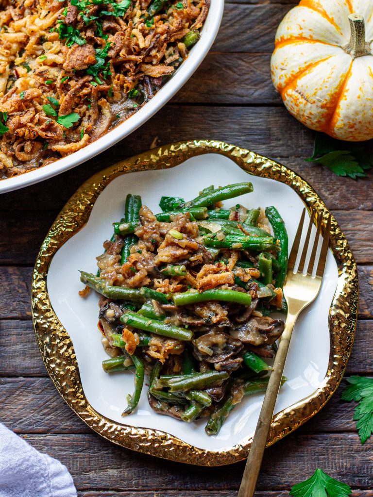 Close-up of a serving of Vegan Green Bean Casserole, showcasing the creamy sauce and crispy onion topping.