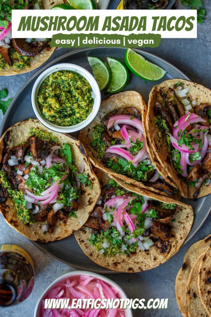 A plate of finished Vegan Asada Mushroom Tacos garnished with fresh lime wedges, cilantro, and hot sauce on the side.