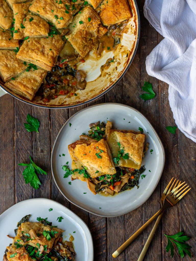 Golden-brown vegan mushroom pot pie with a flaky puff pastry crust, topped with fresh parsley.