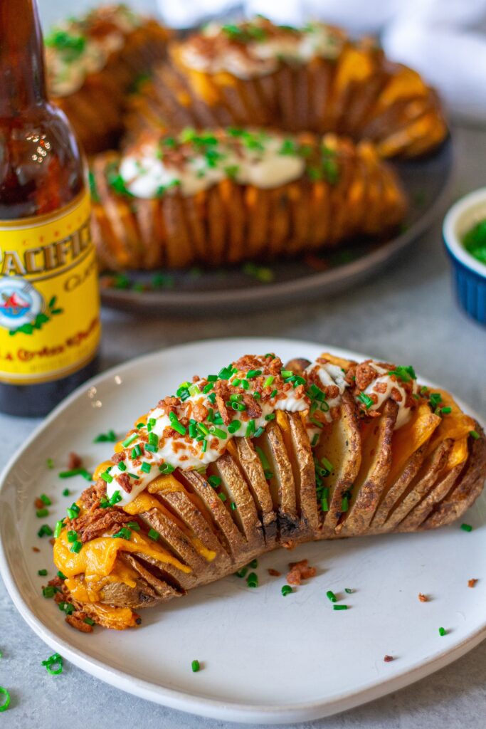 Loaded Hasselback potatoes topped with vegan sour cream, crumbled bac’n bits, and chopped green onions.