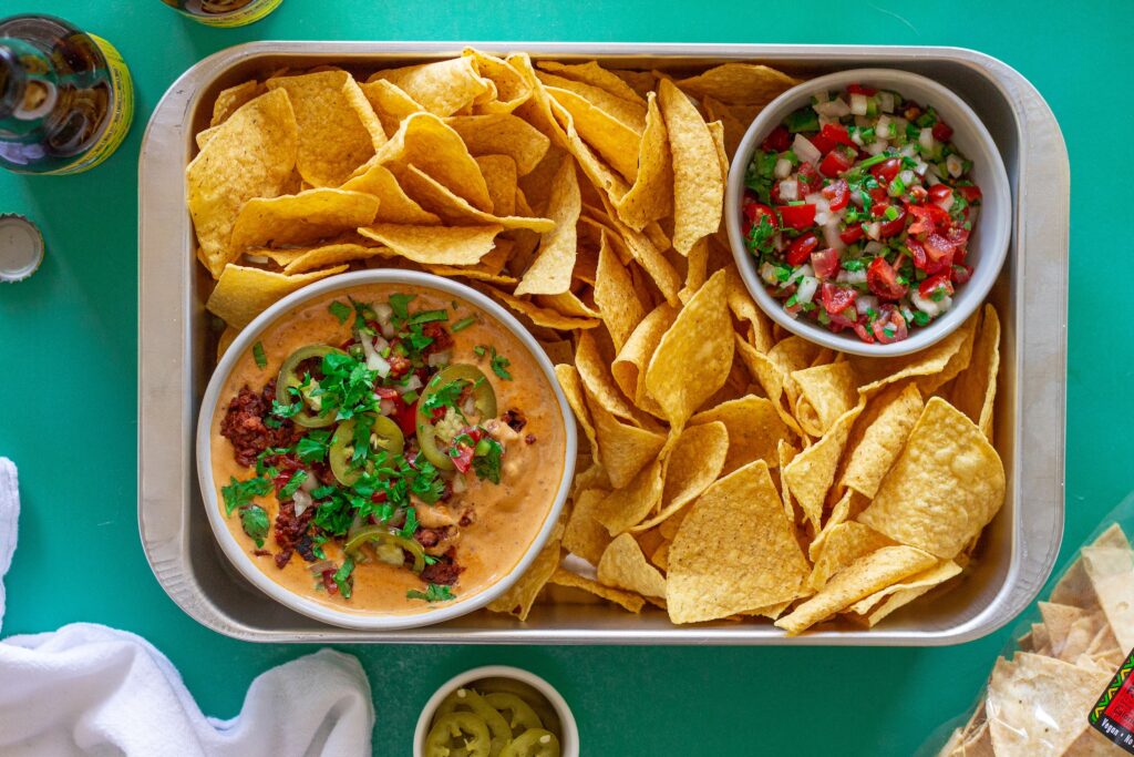 Close-up of creamy vegan queso dip with garnishes, showing the rich texture and colors.