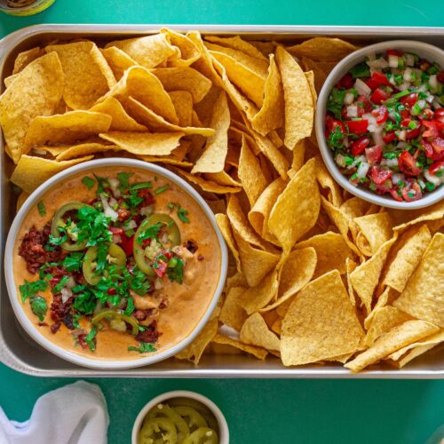 Close-up of creamy vegan queso dip with garnishes, showing the rich texture and colors.