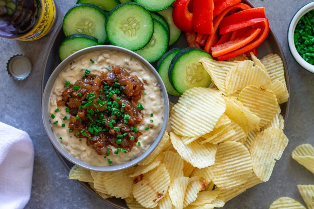 Vegan caramelized onion dip in a bowl, garnished with caramelized onions and minced chives, ready to serve.