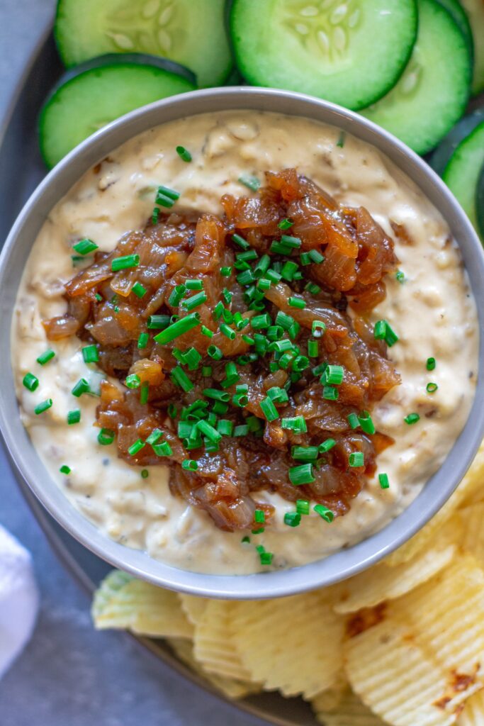 egan caramelized onion dip in a bowl, garnished with caramelized onions and minced chives, ready to serve.