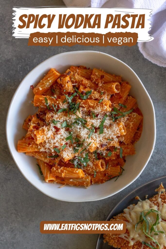 Creamy vegan spicy vodka pasta garnished with fresh basil and red pepper flakes, served in a white bowl.