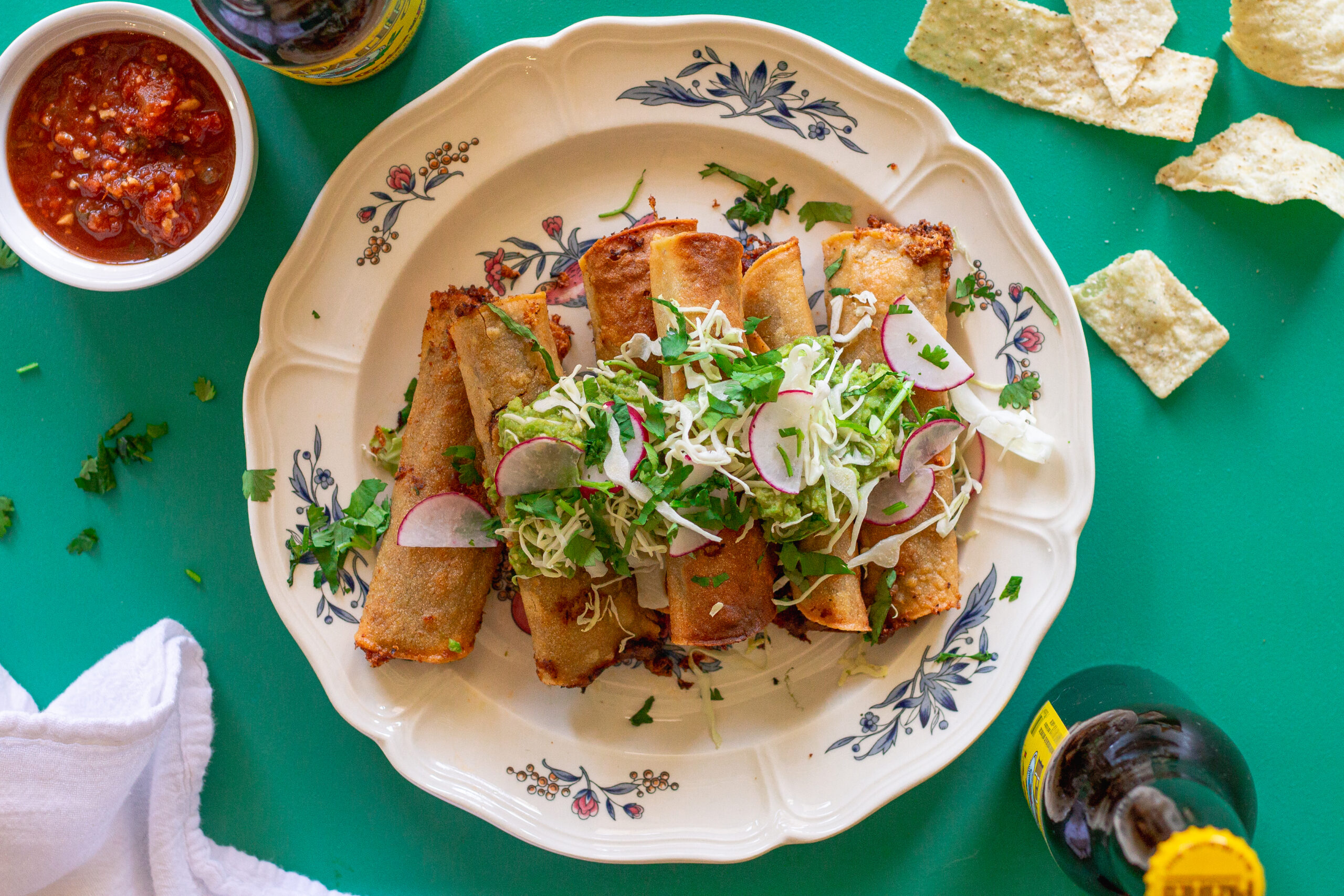 Crispy vegan black bean taquitos served with shredded cabbage and guacamole.