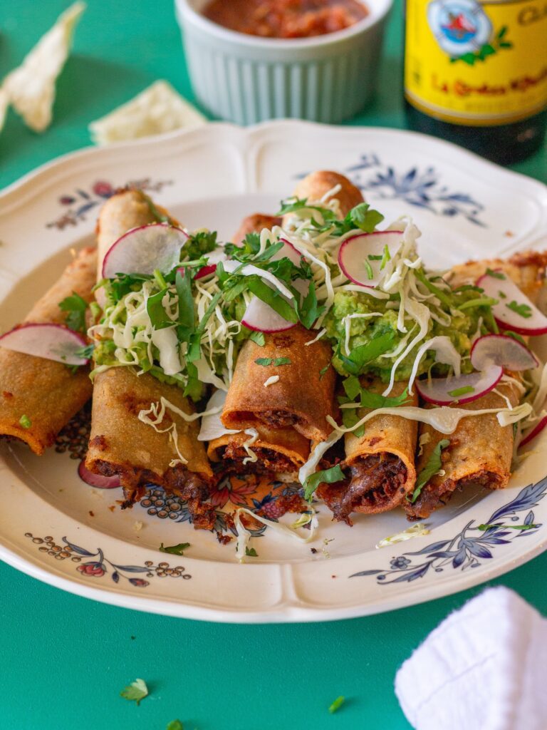 Crispy vegan black bean taquitos served with shredded cabbage and guacamole.