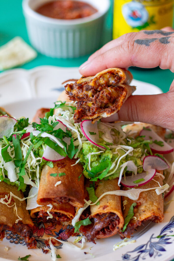 Inside view of a vegan black bean taquito, revealing a seasoned black bean filling with melted vegan cheese.