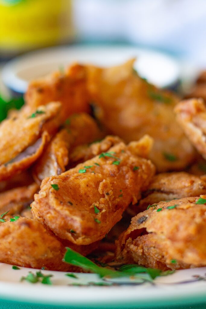 Crispy vegan bloomin' onion petals garnished with fresh parsley, served with a tangy dipping sauce on the side.