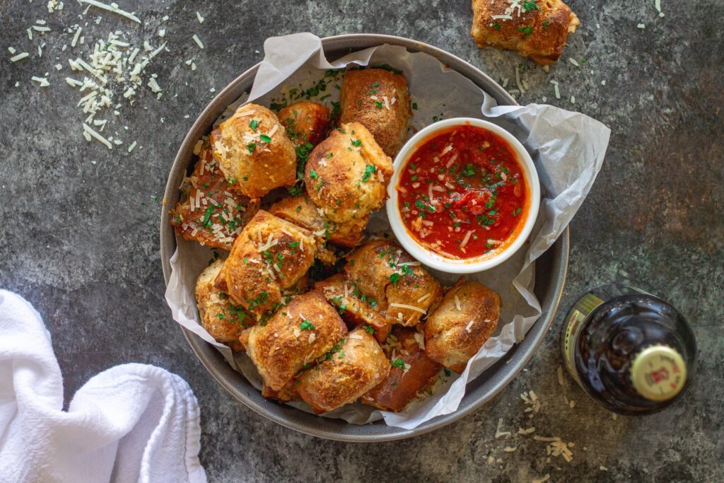 Vegan pizza rolls served on a plate with a side of marinara sauce for dipping.