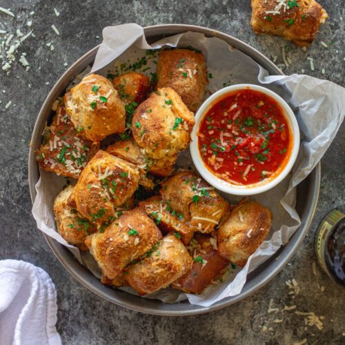 Vegan pizza rolls served on a plate with a side of marinara sauce for dipping.