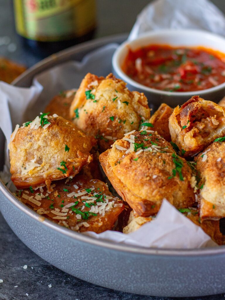 Vegan pizza rolls served on a plate with a side of marinara sauce for dipping.