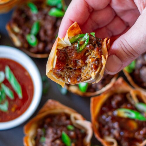 Vegan Lumpia Wonton Cup with a bite taken out, revealing the seasoned vegan ground beef and vegetable filling inside.