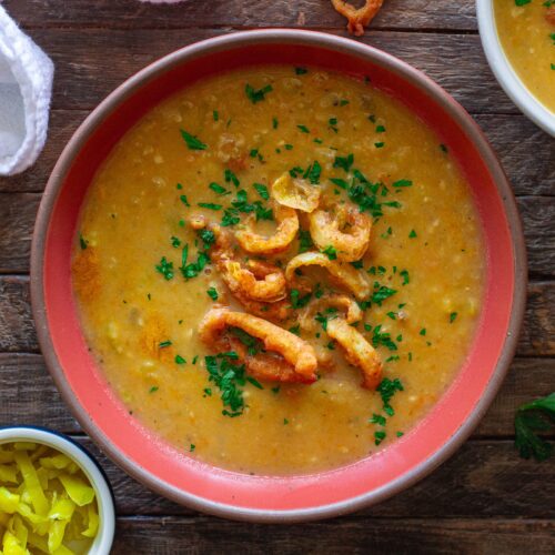 Vegan pepperoncini soup in a bowl, topped with crispy fried pepperoncini rings and fresh minced parsley for garnish.