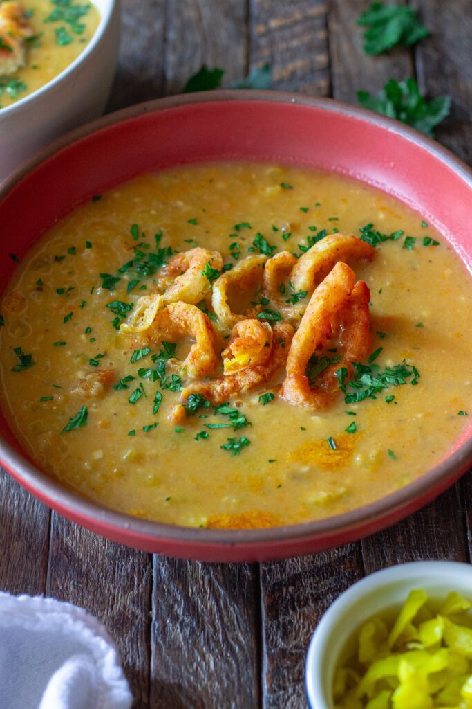 Vegan pepperoncini soup in a bowl, topped with crispy fried pepperoncini rings and fresh minced parsley for garnish.