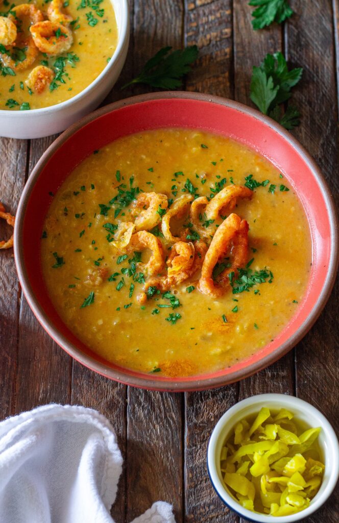 Vegan pepperoncini soup in a bowl, topped with crispy fried pepperoncini rings and fresh minced parsley for garnish.